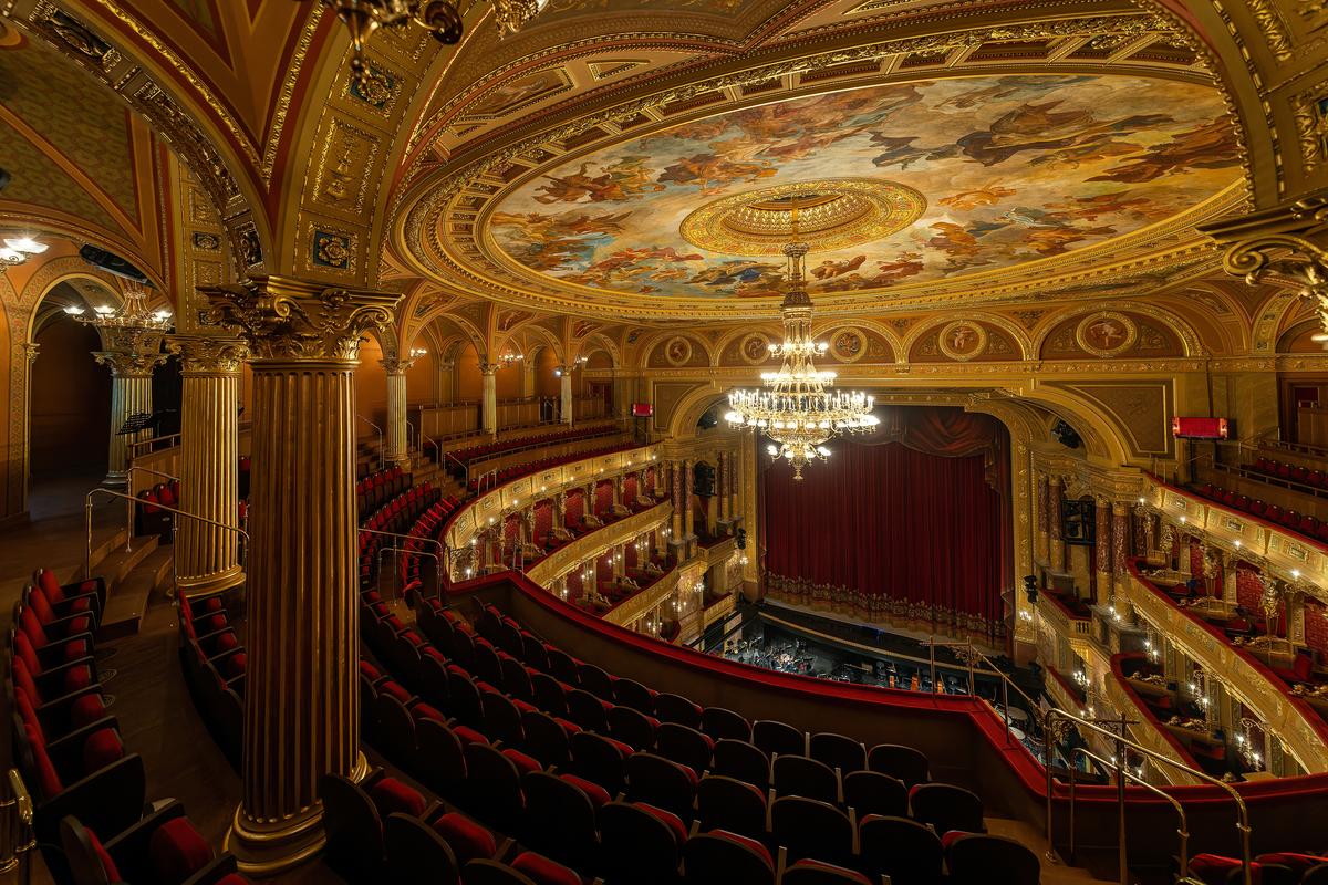 The horseshoe-shaped, three-story auditorium offers visitors a truly theatrical presentation of red and gold hues, a spectacular ceiling fresco, and a focal-point bronze and glass chandelier hanging from inside a cupola. Originally a gas-lit chandelier, the nearly 3-ton fixture is electrically lit with more than 200 bulbs. Resplendent gilded Corinthian columns throughout the auditorium support bedecked arches. (posztos/Shutterstock)