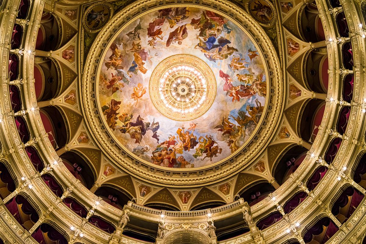 The auditorium’s cupola features the Baroque-style painting “The Apotheosis of Music.” From the view below, symmetrically festooned circles surround the cupola painting and the centerpiece chandelier. Other than the decorative molding around the painting, each of the circular spaces is a level of seating. Adding to the visual presentation are the pointed Gothic arch shapes, which are aspects of the auditorium’s multiple arches. (Jaroslav Moravcik/Shutterstock)