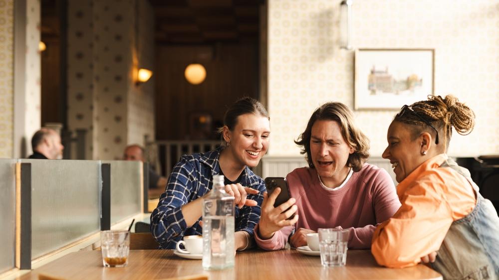 People want and need human interaction on every level. (<a href="https://www.shutterstock.com/g/Rawpixel">Rawpixel.com</a>/<a href="https://www.shutterstock.com/image-photo/three-people-cafe-smiling-looking-phone-2573925359?trackingId=067f3d8f-e06e-4cef-ae50-8c6c4678018b&listId=searchResults">Shutterstock</a>)