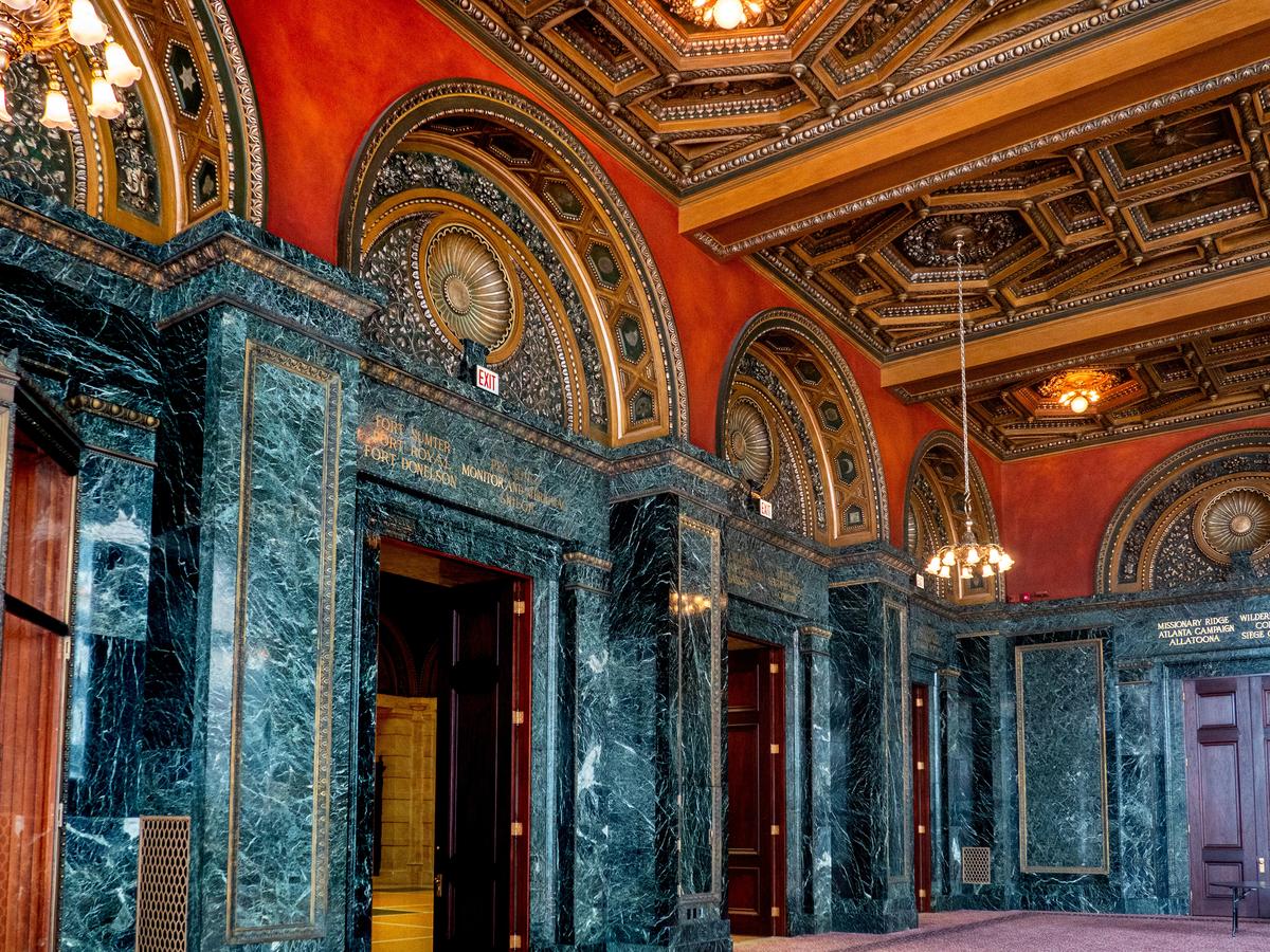 Featuring nine pairs of 14-foot-high mahogany doors, as well as cherrywood-lined display cases, the Grand Army of the Republic Hall was initially used as a museum for Civil War artifacts. The hall’s name originated as a way to honor Union veterans. In fact, the wood cases once displayed such memorabilia as Ulysses S. Grant’s saddle, Gen. William T. Sherman’s uniform, and George Custer’s hat. Its variegated, dark green marble columns and walls are trimmed in bronze. Silver leaf embellishments in the metal and plaster ornamentation within the half arches and coffered ceiling represent different Civil War regimental symbols. Most are outlined in such classic molding design trims as bead or rope. (bodhichita/Shutterstock)