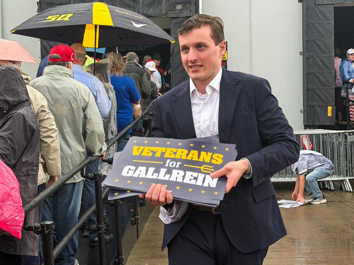 A volunteer passes out signs for Republican congressional candidate Ed Gallrein at Verst Logistics in Hebron, Ky., on March 11, 2026. (Janice Hisle/The Epoch Times)