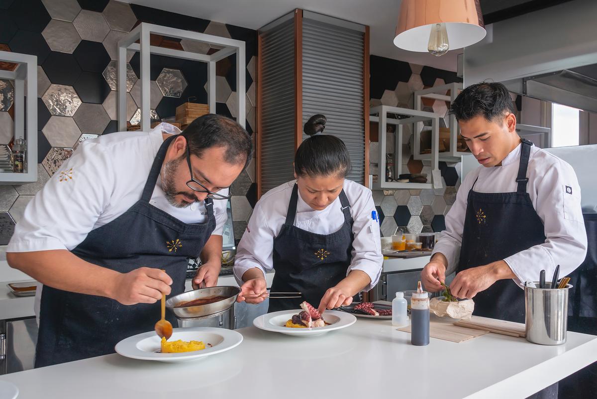 Inés Restaurant owner and chef Juan Carlos Donoso, kitchen manager Gema de la Cruz, and scholarship program intern Anthony Cox preparing “octopus passion.” (Maria Coulson)