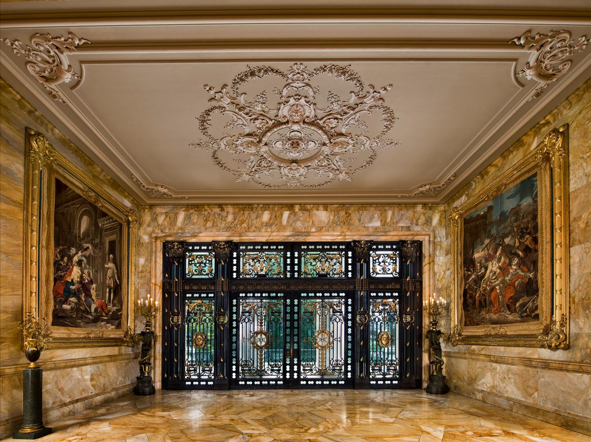 As one crosses the threshold through the grand 16-foot-high bronze doors, each weighing 3,000 pounds, Marble House immediately asserts its presence. Every detail speaks to a design built not merely to impress, but also to endure. Flanking the entrance, two late 18th-century Gobelins tapestries command the space. Woven with wool and silk at Paris's legendary Manufacture des Gobelins, these painterly masterworks have graced the world's most distinguished residences for centuries. (The Preservation Society of Newport County)