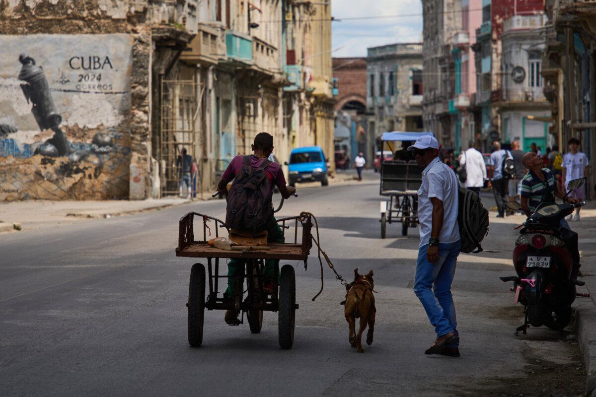 A man rides a tricycle with his leashed dog running alongside him during a blackout in Havana, Cuba, on March 16, 2026. (Ramon Espinosa/AP Photo)