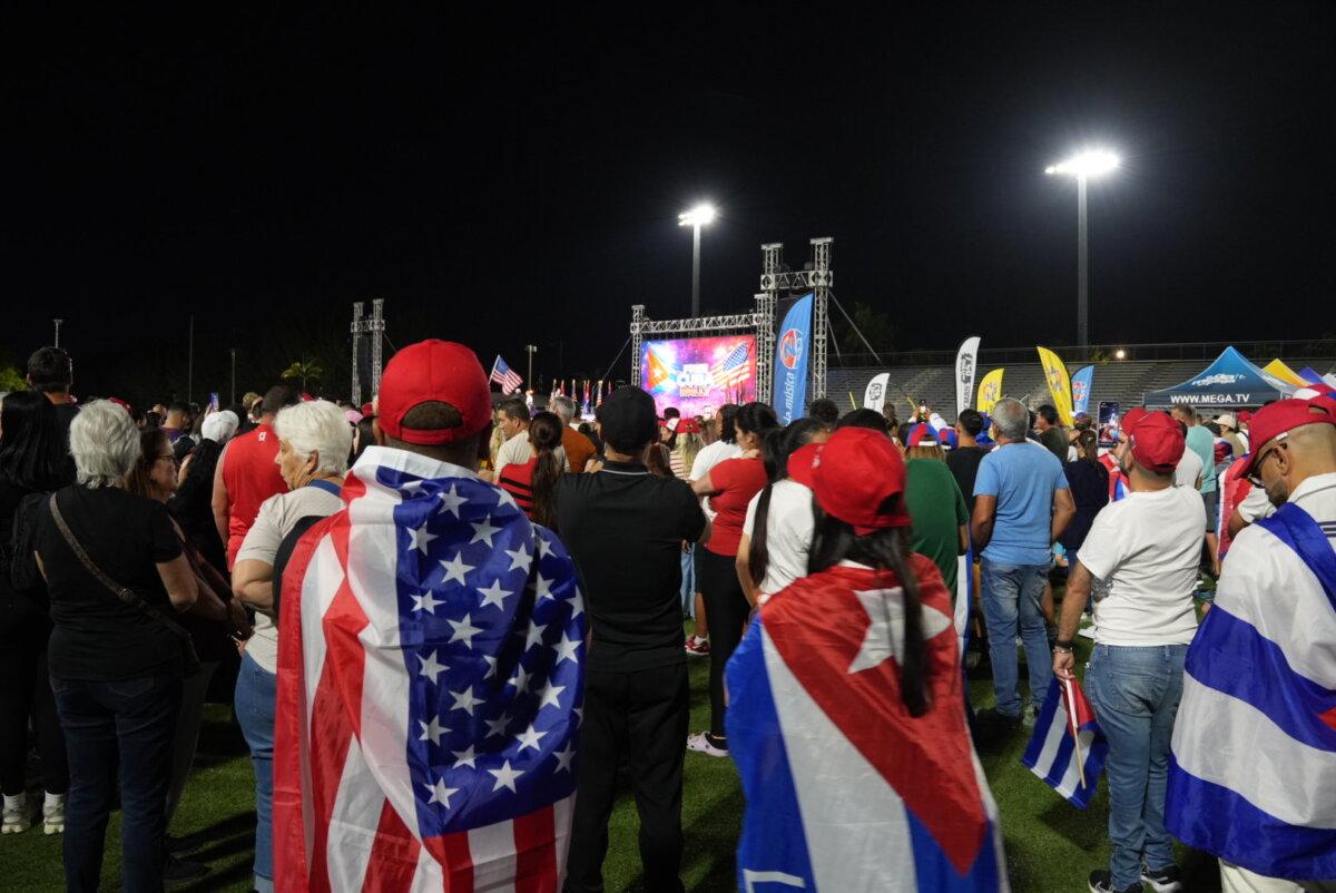 Cuban Americans draped their country and the U.S. flag around themselves at a rally for a post-regime Cuba, in Hialeah, Fla., on March 25, 2026. (Troy Myers/The Epoch Times)