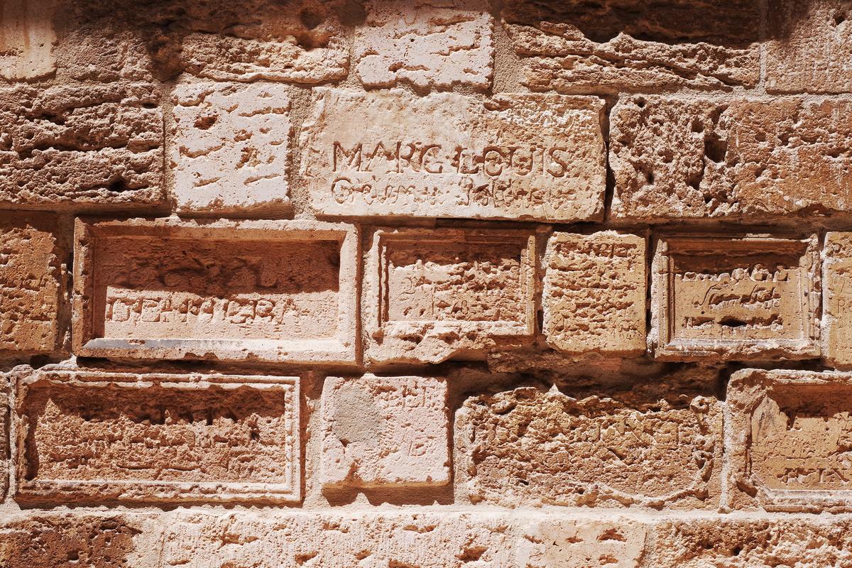 A close-up of the limestone walls shows inscriptions etched by French prisoners between 1848 and 1849. (Erin N/Shutterstock)