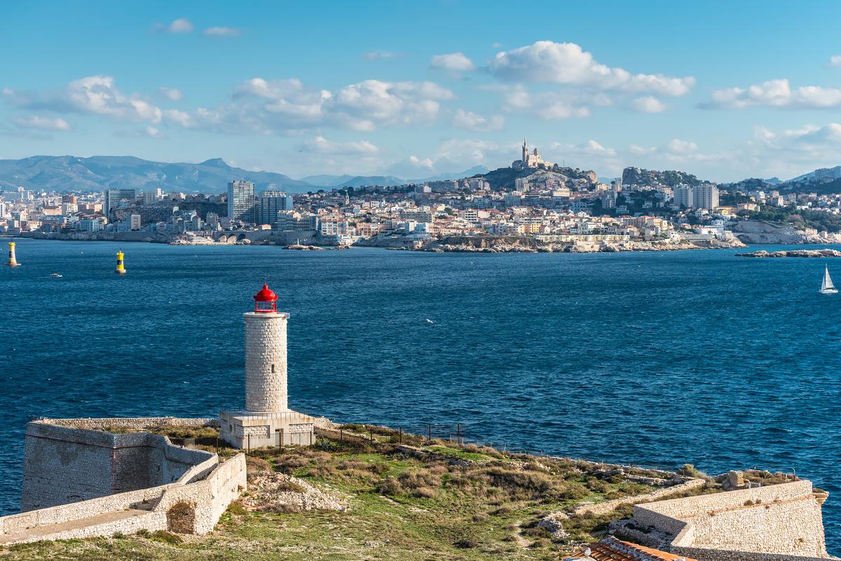 A white, round stone lighthouse rises from a square base, topped with a bright red lantern. The tower stands 56 feet tall. It replaced the original 31-foot lighthouse, which was destroyed by German forces in 1944 during World War II and rebuilt in 1948. Its light emits two white flashes every six seconds, visible for up to 11 nautical miles. (byvalet/Shutterstock)