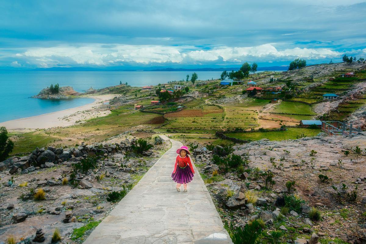 Resplendent Quechua girl walking up a stone pathway on Taquile Island. (Maria Coulson)