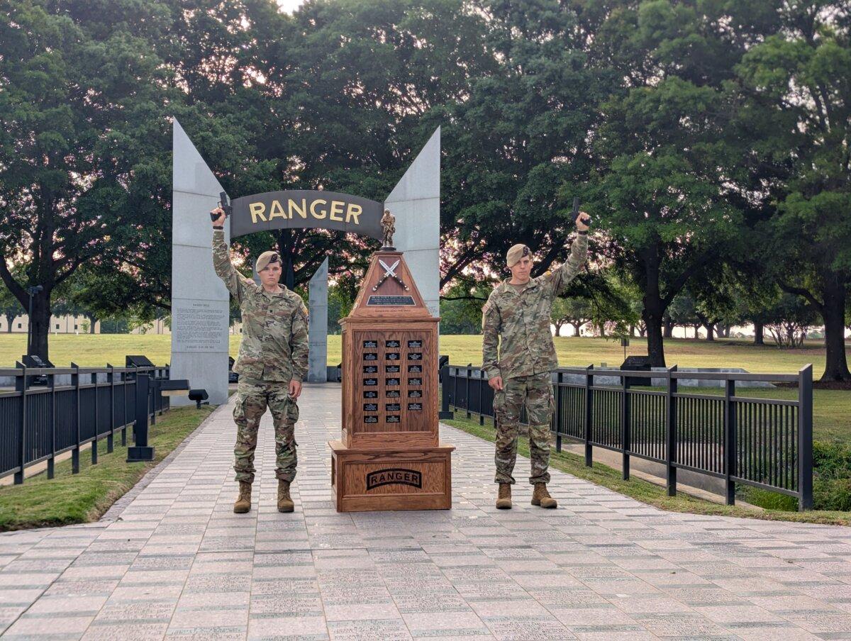Spc. Caleb Godbold (L) and Sgt. Drew Schorsch (R) raise custom Staccato P4X pistols over their heads in front of the National Ranger Memorial at Fort Benning, Ga. The two-man team, representing the 75th Ranger Regiment, received the pistols as their prize for winning the 2026 Best Ranger Competition. (Ryan Morgan/The Epoch Times)