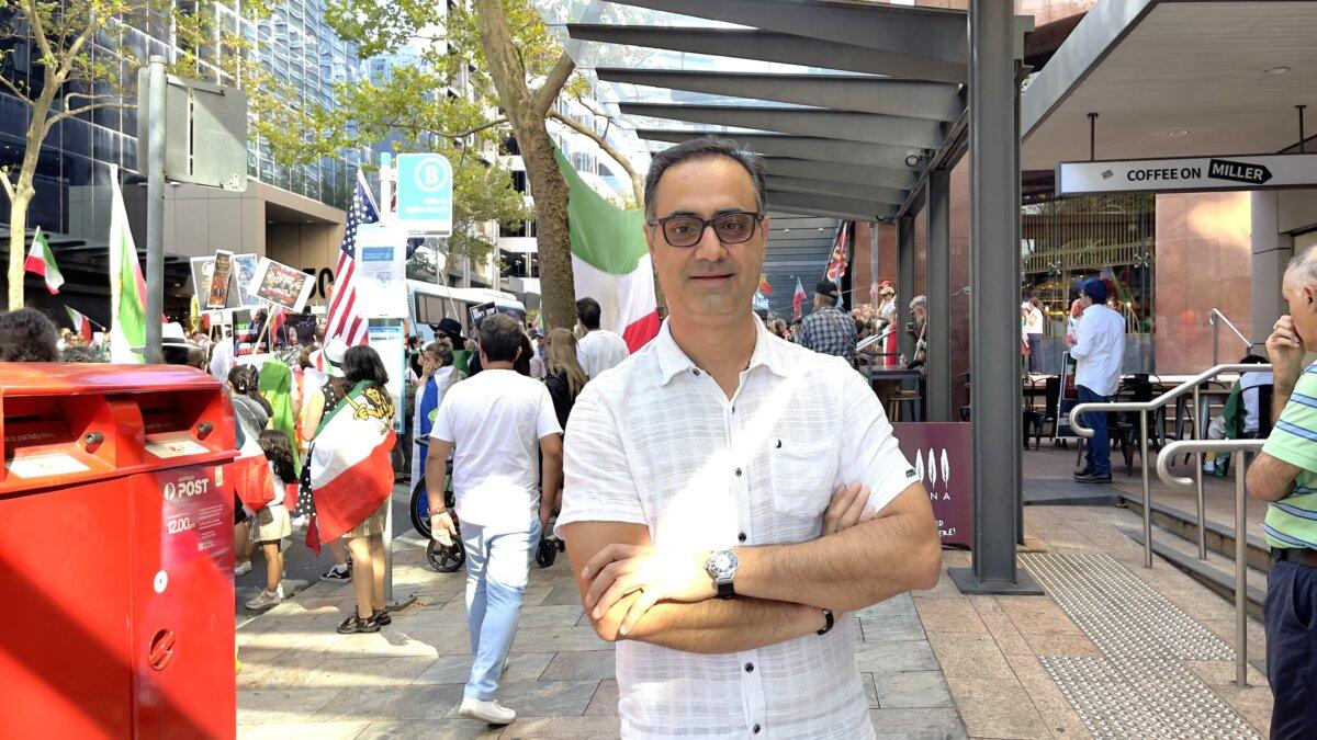 David Archer explains why paying more at the bowser is worth securing freedom in Iran, during a protest outside the U.S. consulate building in Sydney, Australia on April 11, 2026. (Adam Chiang/The Epoch Times)