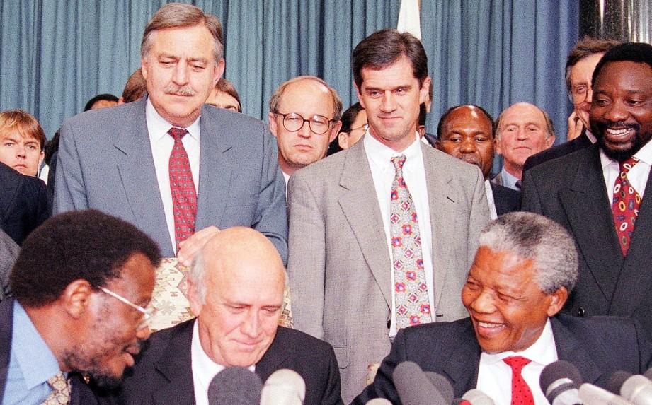 Roelf Meyer (back C) stands next to Cyril Ramaphosa (back R) and behind Nelson Mandela (front R) and then-President F.W. de Klerk (front C) during a press conference in Pretoria, South Africa, on April 19, 1994. (Lynne Sladky/AP)