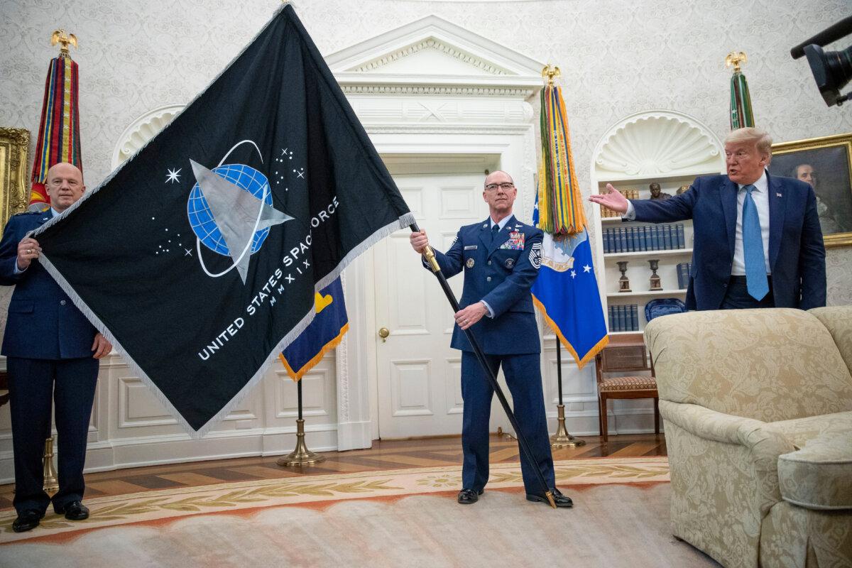 Gen. John "Jay" Raymond (L), Commander of U.S. Space Command, and Chief Master Sgt. Roger Towberman (C) hold the Space Force Flag as President Donald Trump gestures to it during the presentation in the Oval Office of the White House in Washington on May 15, 2020. (AP Photo/Alex Brandon, File)