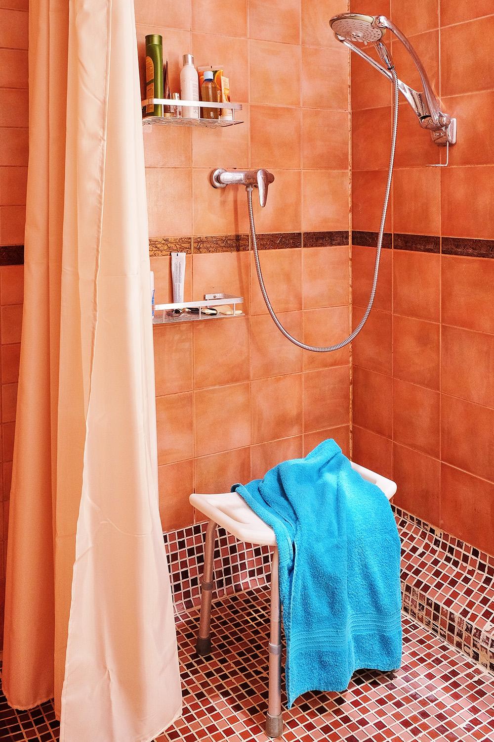 Shower chairs provide a stable seating option, while barrier-free shower designs make it easier to enter and leave. (artichoke studio/Shutterstock)