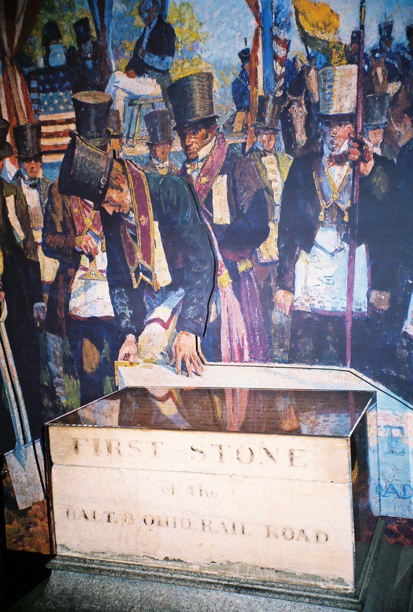 The Baltimore & Ohio Railroad cornerstone is displayed at the B&O Railroad Museum under a painting depicting Charles Carroll of Carrollton, the last living signer of the Declaration of Independence, at a groundbreaking ceremony on July 4, 1828. (Public Domain)