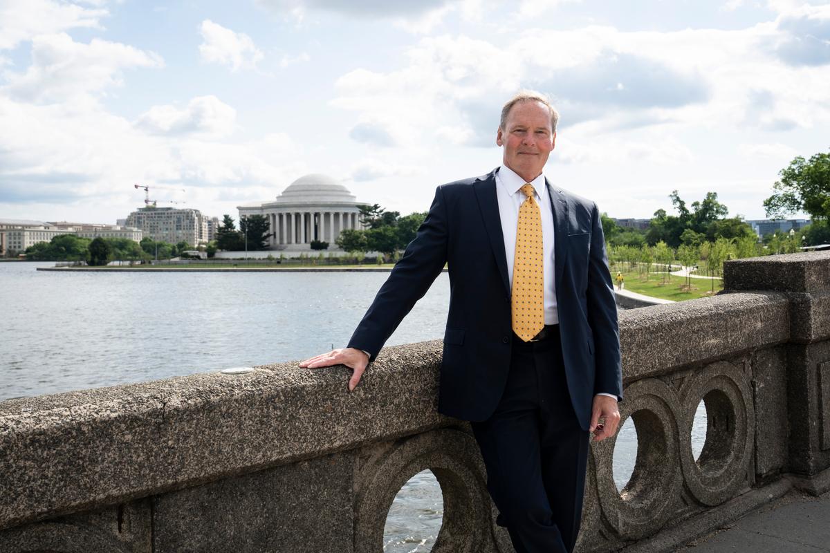 Michael Curtis poses on the Inlet Bridge with the neoclassical Thomas Jefferson Memorial across the Tidal Basin in Washington, DC. (Madalina Kilroy/The Epoch Times)