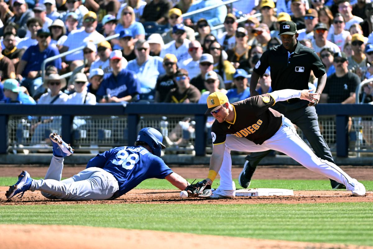 James Tibbs III #98 of the Los Angeles Dodgers safely dives back to first base as Gavin Sheets #30 of the San Diego Padres attempts to make a play on a throw in the dirt during the second inning of a spring training game at Peoria Stadium in Peoria, Arizona, on Feb. 22, 2026. (Norm Hall/Getty Images)