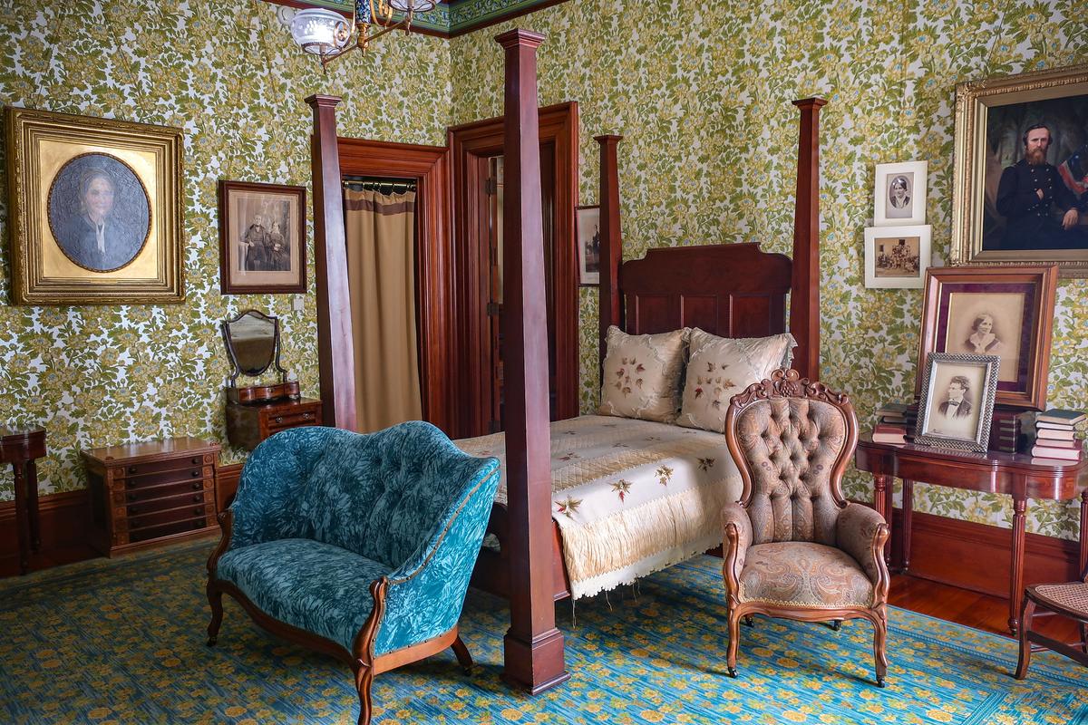 In the Hayes’s bedroom is their four-poster bed with tall, square, column-like posts. On the bed is an original bed covering intricately hand-embroidered by a Hayes cousin. A Victorian-style, blue velvet button and wood-trimmed settee and a button-tufted, pink damask chair coordinate with the sumptuous floral wallpaper. This room is heavily apportioned with historic black-and-white photographs of the Hayeses, as well as a rare photograph of a young Abraham Lincoln and paintings of family members. (Hayes Presidential Library & Museums)