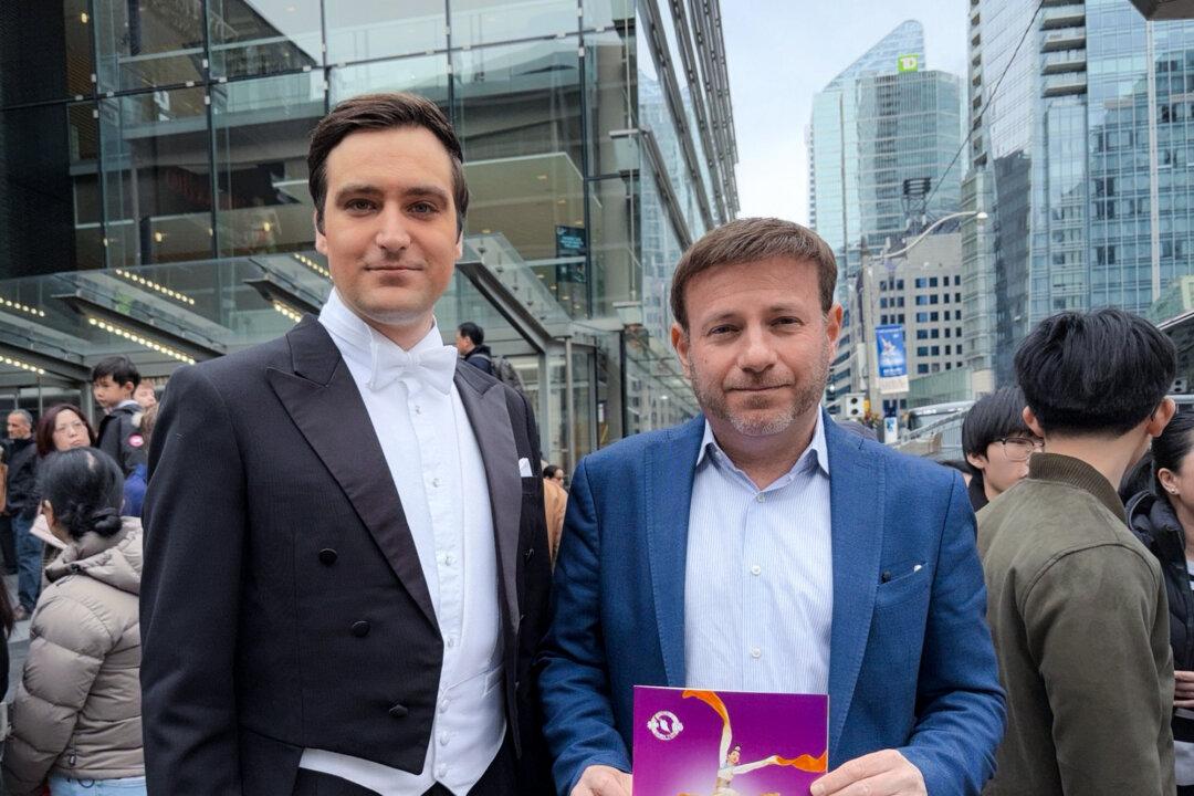 Conservative MP Roman Baber holds a Shen Yun program book while standing with a show host outside the Four Seasons Centre for the Performing Arts in Toronto on March 29, 2026. (The Epoch Times)