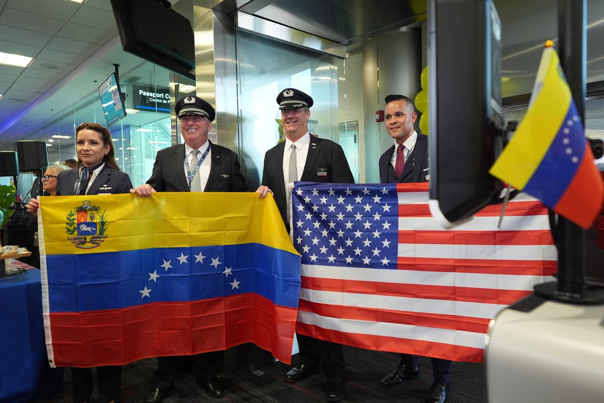 Capt. Ric Wilson (center left) and first officer Robert Neider (center right) hold Venezuelan and American flags along with other members of the American Airlines Flight AA3599 flight crew, as they prepare to pilot the first direct commercial flight between the United States and Venezuela in seven years at Miami International Airport on April 30, 2026. (AP Photo/Rebecca Blackwell)