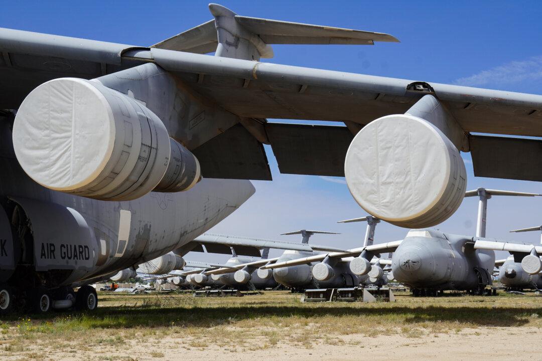 (Top) A row of military helicopters in storage at the 309th Aerospace Maintenance and Regeneration Group in Tucson, Ariz., on April 21, 2026. (Bottom) A C-5 Galaxy cargo plane with a 223-foot wingspan overshadows other military aircraft in storage at the “Boneyard” at Davis-Monthan Air Force Base in Tucson, Ariz., on April 21, 2026. (Allan Stein/The Epoch Times)