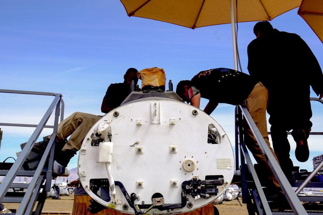 (Left, Right) Workers at the 309th Aerospace Maintenance and Regeneration Group remove the pilot ejection system at Davis-Monthan Air Force Base in Tucson, Ariz., on April 21, 2026. The facility employs more than 700 workers and encompasses more than half a million square feet of industrial space. (Allan Stein/The Epoch Times)