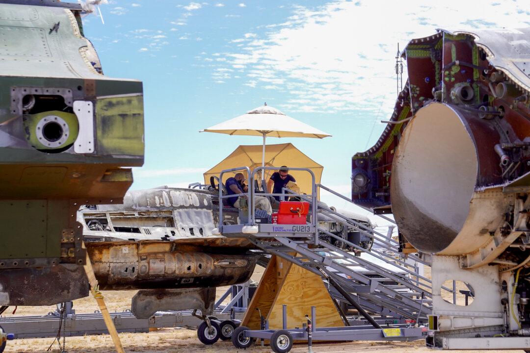 (Left, Right) Workers at the 309th Aerospace Maintenance and Regeneration Group remove the pilot ejection system at Davis-Monthan Air Force Base in Tucson, Ariz., on April 21, 2026. The facility employs more than 700 workers and encompasses more than half a million square feet of industrial space. (Allan Stein/The Epoch Times)