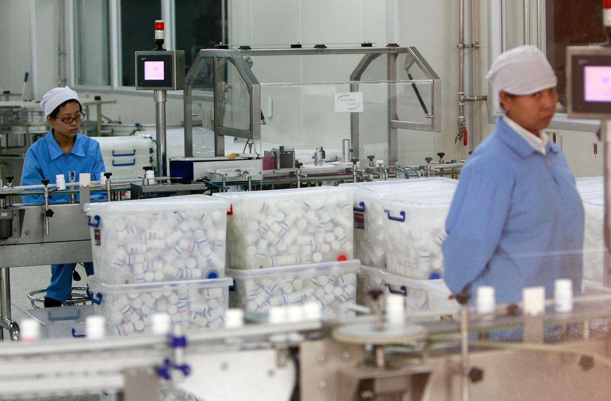 Chinese workers watch the production line for pill capsules at the Tongrentang factory in Beijing on Aug. 3, 2007. (Teh Eng Koon/AFP via Getty Images)