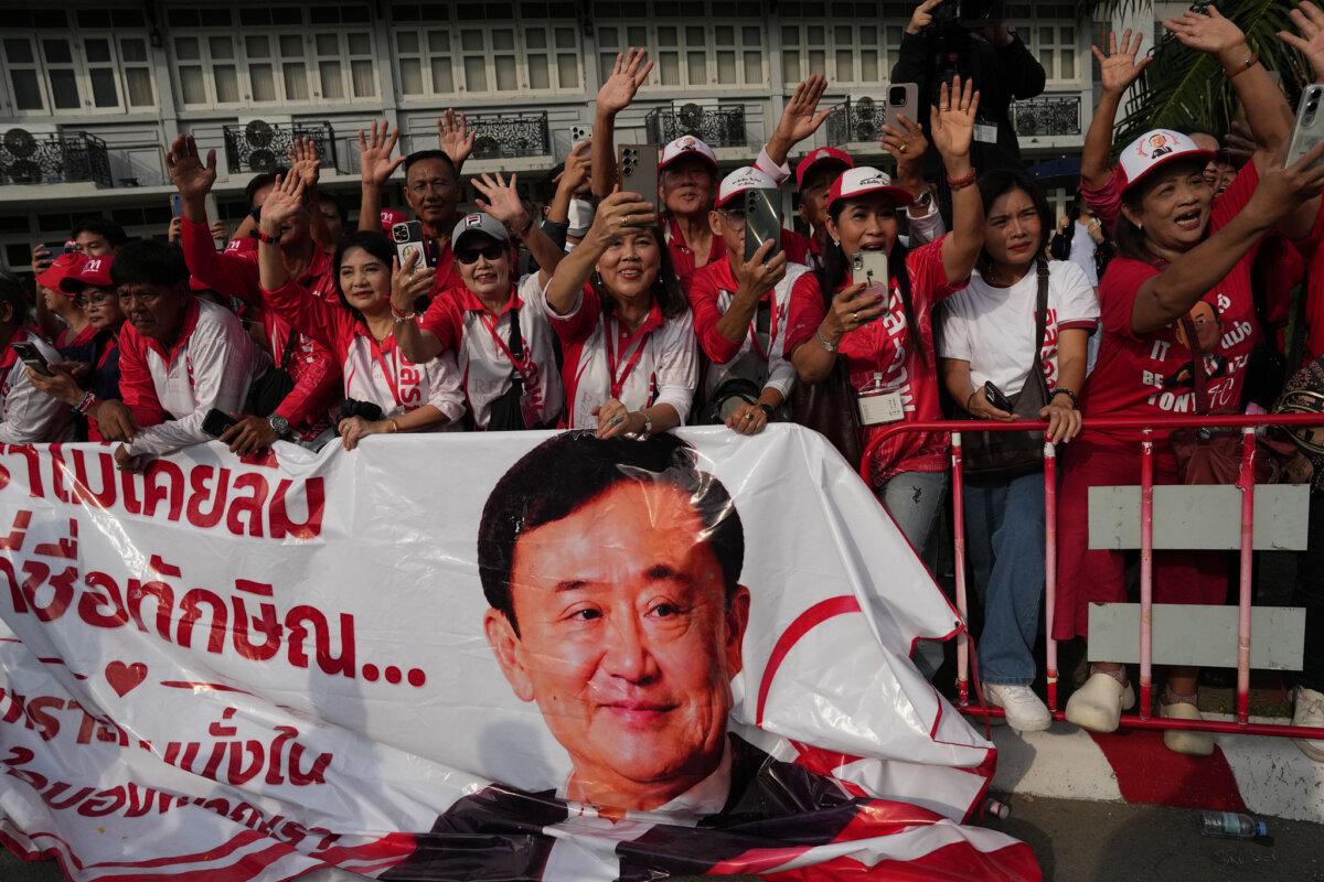 Supporters of former Thailand Prime Minister Thaksin Shinawatra wave and hold banner after he was released on parole from a prison in Bangkok on May 11, 2026. (Sakchai Lalit/AP Photo)