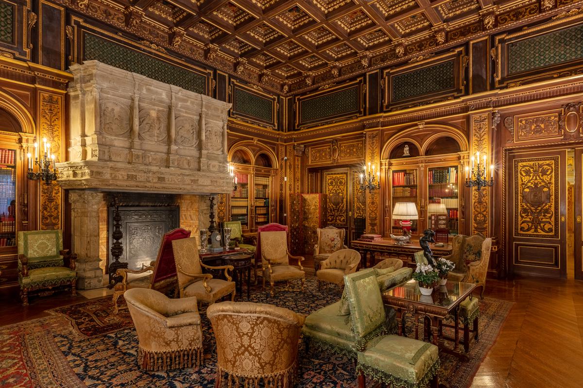 The library features coffered ceilings painted with dolphins, Renaissance symbols of love and protection. The walls of Circassian walnut paneling are detailed with gold leaf to resemble a leather-bound book. Green Spanish leather, embossed with gold, lines the space between the ceiling and paneling. The 16th-century French fireplace carries the inscription "I laugh at great wealth, and never miss it; nothing but wisdom matters in the end." (The Preservation Society of Newport County)