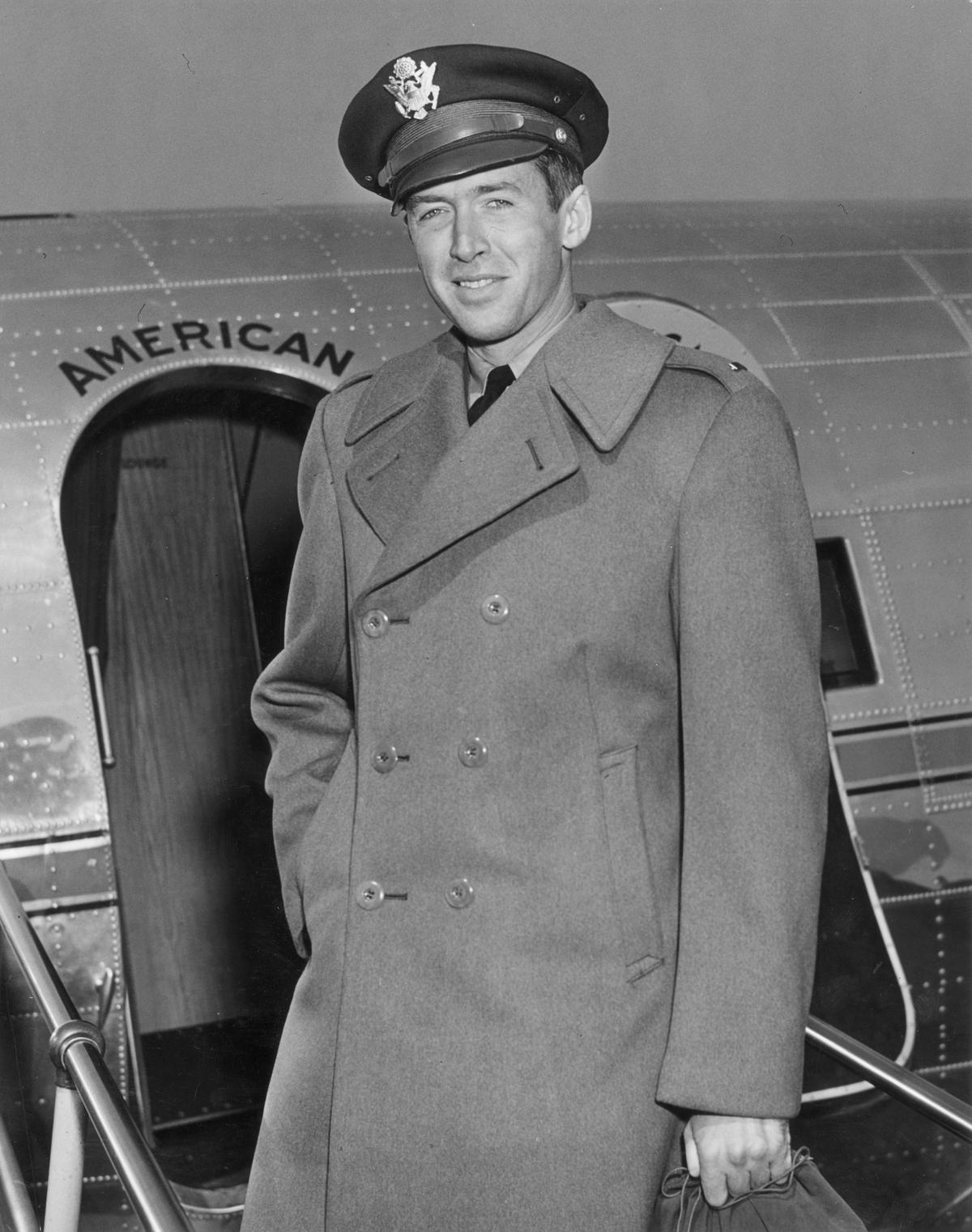 A circa 1942 portrait of American actor Jimmy Stewart standing in front of a military airplane in his Air Force cap and wool overcoat. (Hulton Archive/Getty Images)