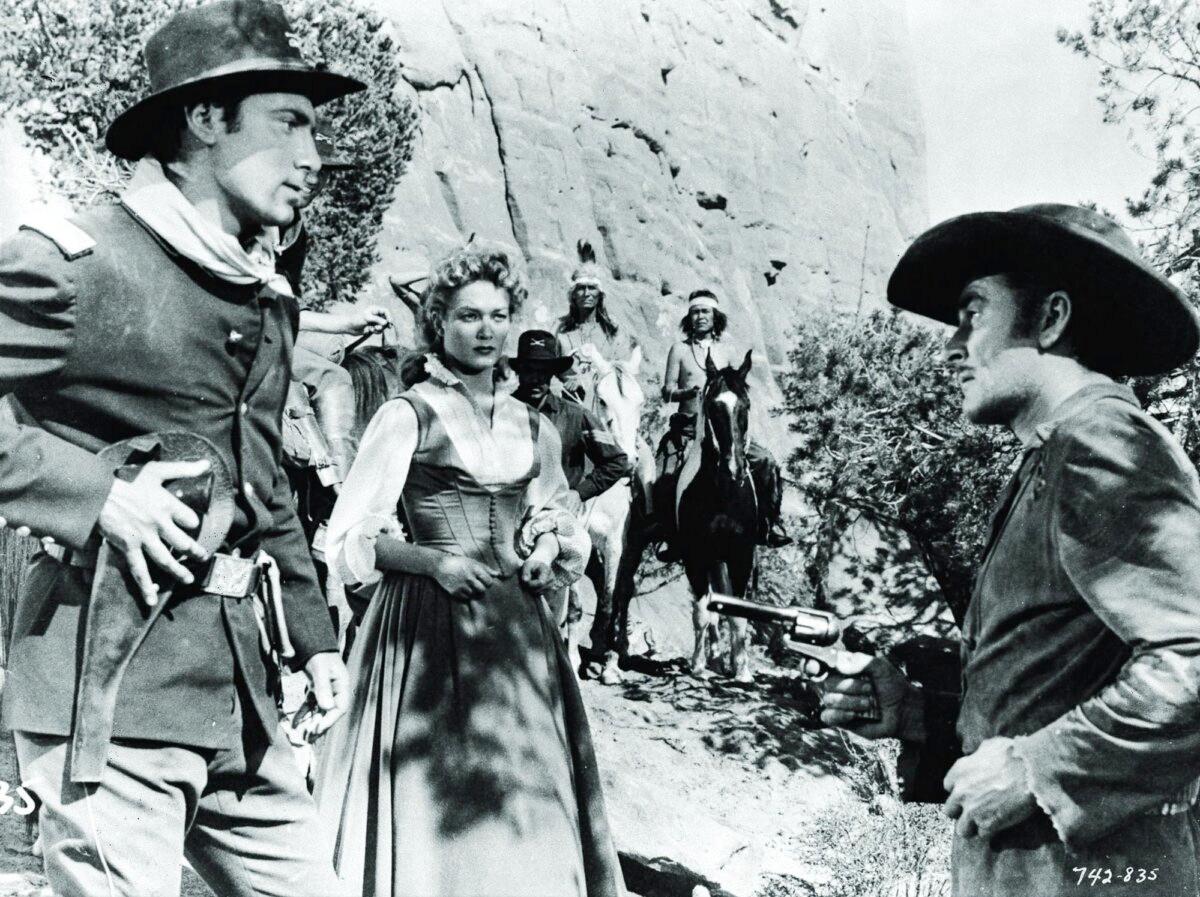 (L–R) Lt. Rickey (Scott Forbes), Johanna Carter (Patrice Wymore), Chief Man Dog (Nakai Snez in background), and Capt. Lafe Barstow (Errol Flynn), in “Rocky Mountain.” (Warner Bros. Pictures)