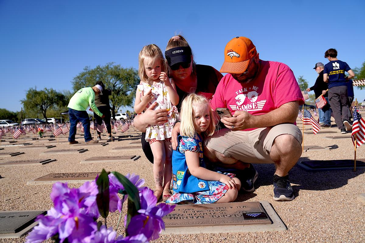Brian Barnum (R), wife Loralee, and daughters Elizabeth, 5, and Lucy, 3, kneel before the grave marker of Brian's grandfather, George Barnum, a WWII U.S. Army Air Corps veteran. (Allan Stein/The Epoch Times)
