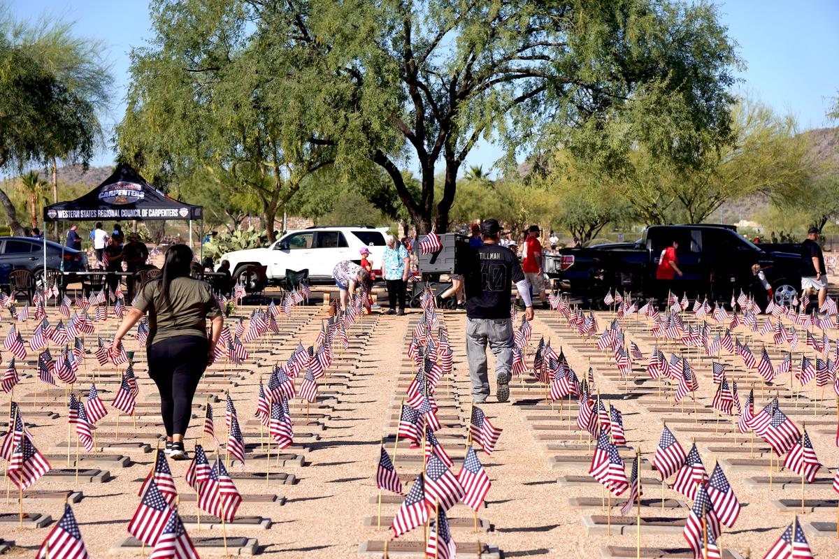 Volunteers work under a hot morning sun placing flags at veteran grave markers in Phoenix on May 23, 2026. (Allan Stein/The Epoch Times)