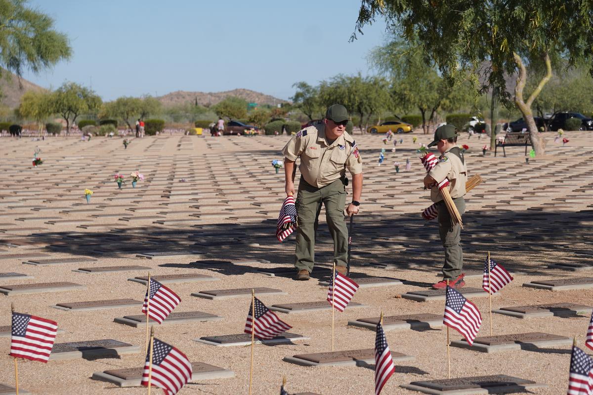 Benjamin Stepp (L) and a Cub Scout from Pack 990 in Phoenix dig holes for placing flags at veteran graves in Phoenix on May 23, 2026. (Allan Stein/The Epoch Times)