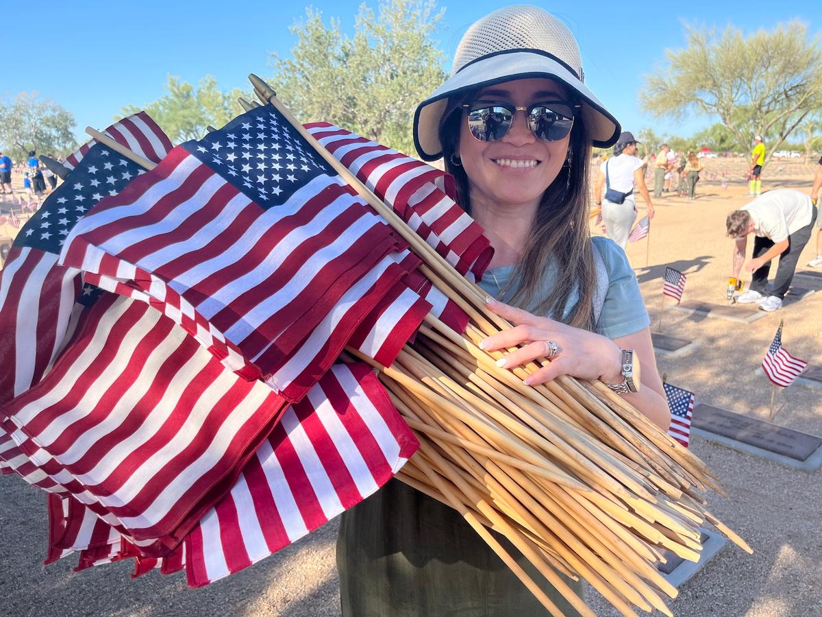 A volunteer clutches flags for veteran grave markers in Phoenix on May 23, 2026. (Allan Stein/The Epoch Times)