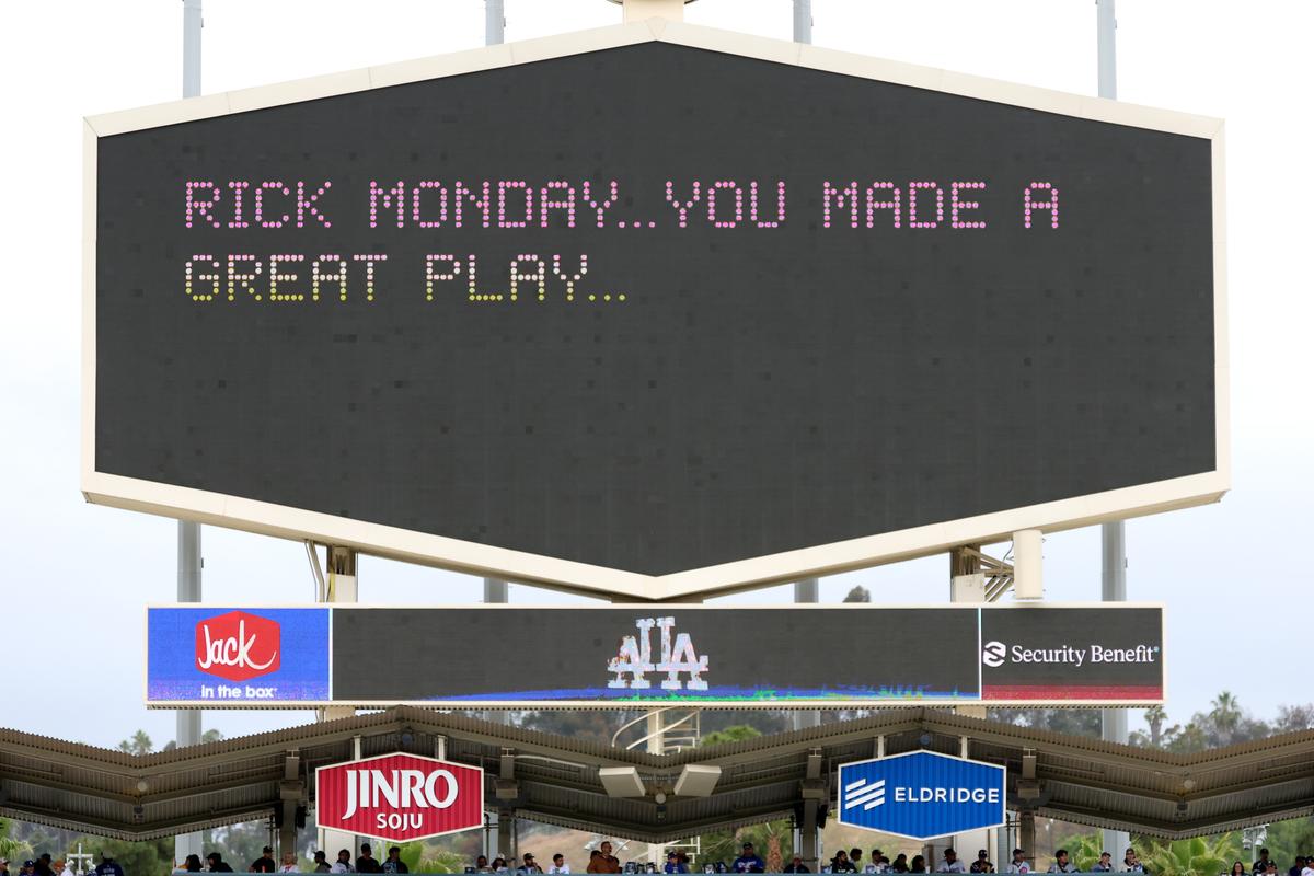 The scoreboard displays "Rick Monday ... You Made a Great Play" to honor the 50th anniversary of a flag being saved from burning before the game between the Los Angeles Dodgers and the Chicago Cubs at Dodger Stadium in Los Angeles on April 25, 2026. (Harry How/Getty Images)