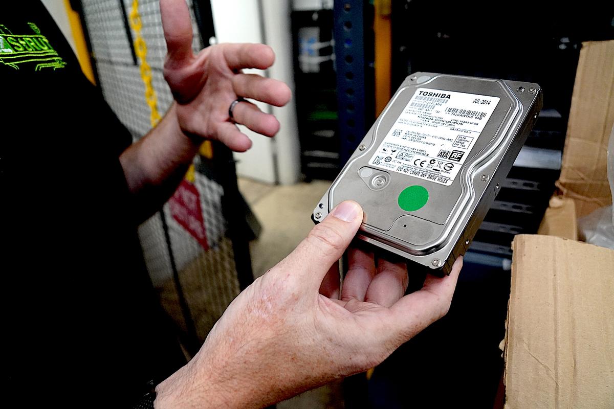 Jared Bodine, executive director of Arizona StTRUT, shows an old computer hard drive that has been wiped clean for reuse in another device on May 20, 2026. (Allan Stein/The Epoch Times)