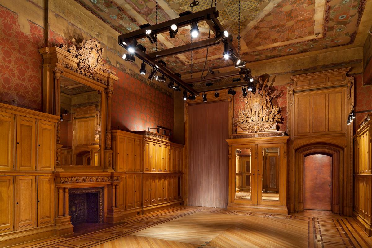Originally designed in 1880 by Pottier & Stymus in a Renaissance Revival style, Company E’s striking interior underwent alterations in the 1890s that included Tudor-style plasterwork and new wallpaper. The 2010 restoration thoughtfully reestablished the original decorative scheme of stenciled red and copper walls and warm oak woodwork that glows again. (James Ewing/Park Avenue Armory)