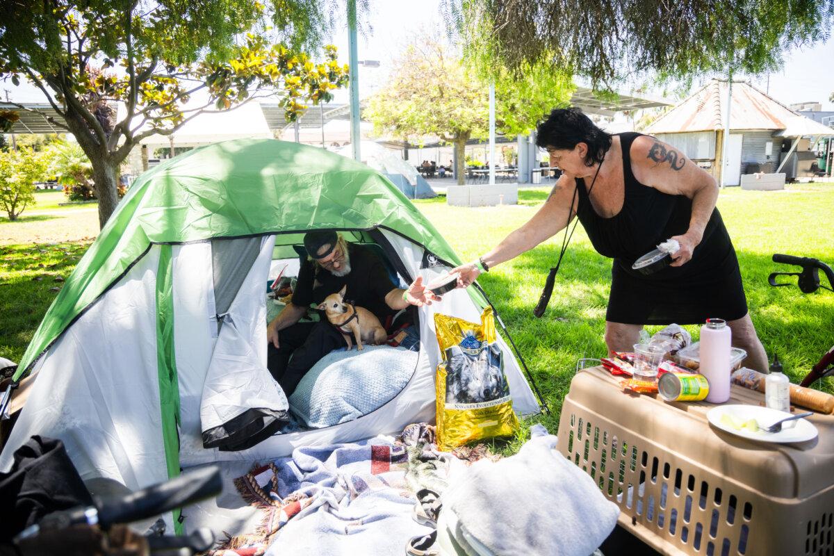 Jan De Jonge and her fiancé, Sher Stuckman, set up a tent with their belongings and pet outside the Elks Lodge in Garden Grove, Calif., on May 25, 2026. (AP Photo/Ethan Swope)