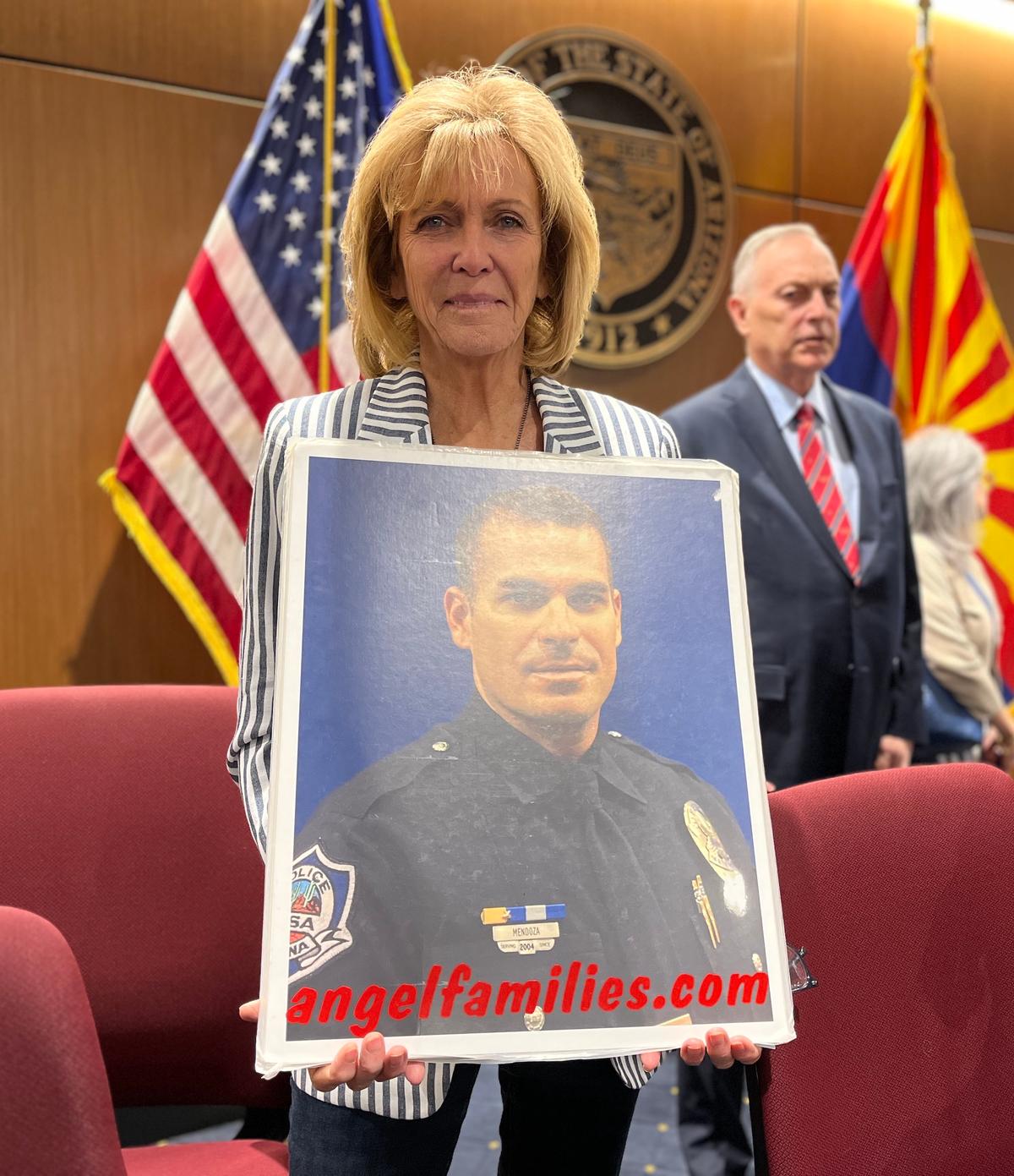 Mary Ann Mendoza holds a picture of her son, Brandon, killed by an illegal immigrant driver in 2014. At right is U.S. Congressman Andy Biggs (R-Ariz.). (Allan Stein/The Epoch Times)