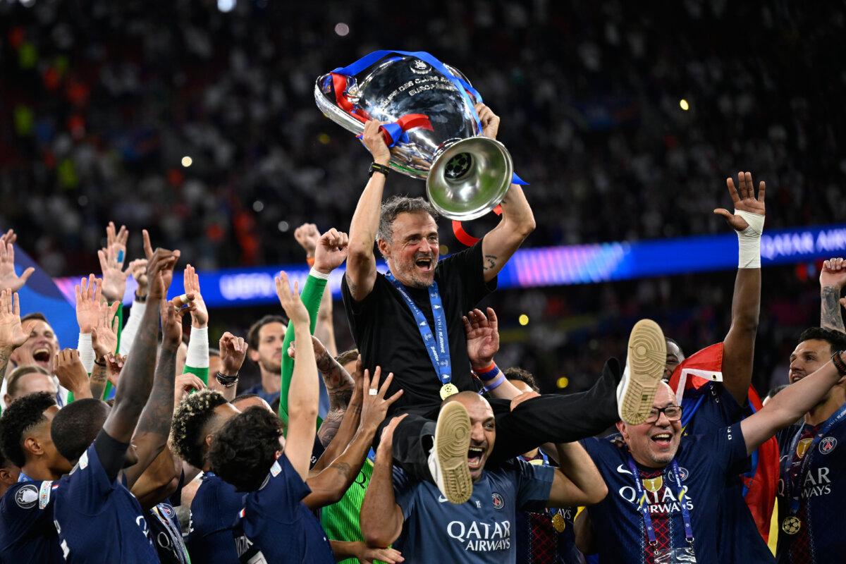 Paris Saint-Germain's head coach Luis Enrique holds the Champions League trophy aloft as he celebrates with players after beating Arsenal in Budapest, Hungary, on May 30, 2026. (Denes Erdos/AP)