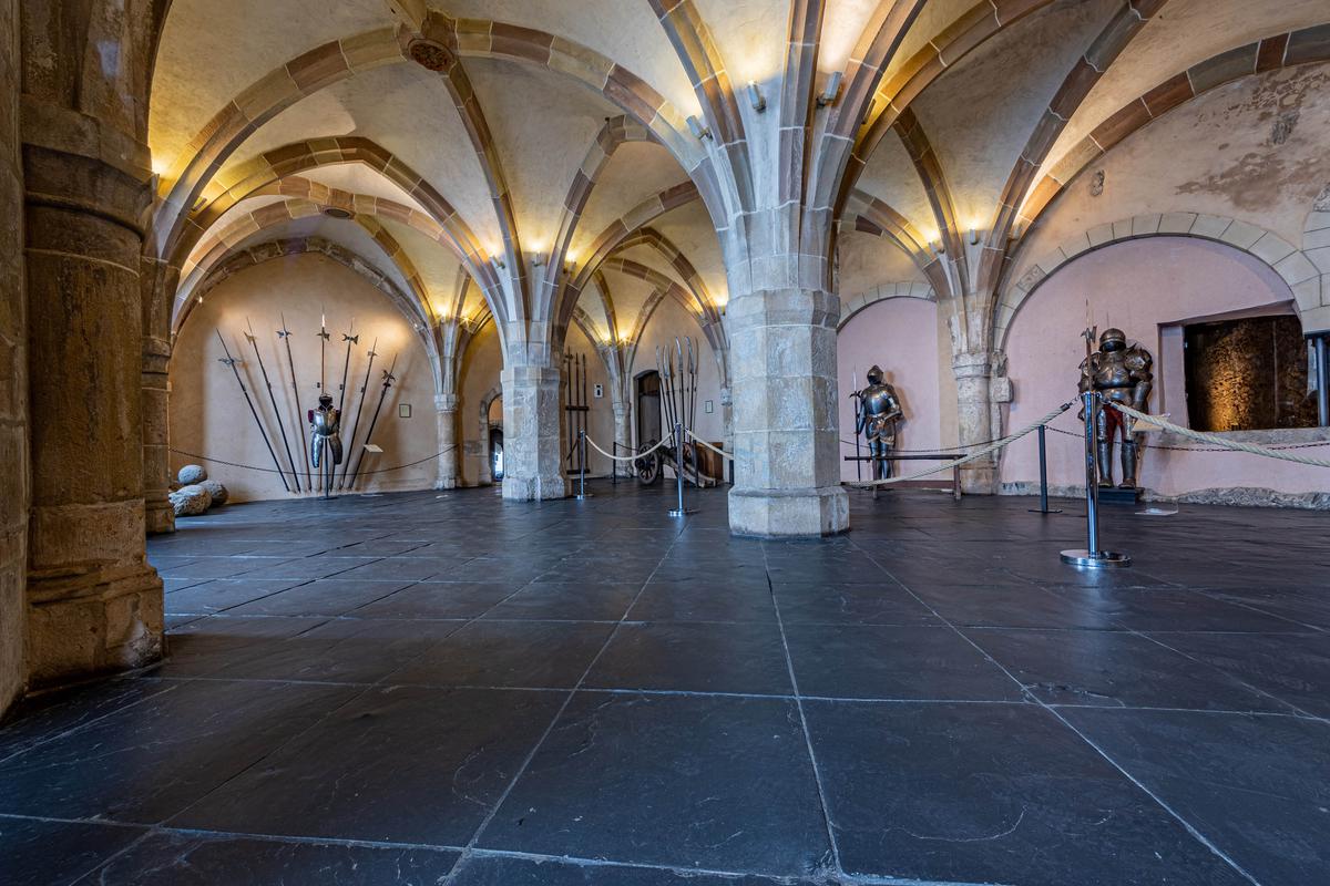 A rib-vaulted ceiling, with contrasting color stone blocks and Gothic arches provides the backdrop for medieval body armor, cannons, and weaponry artifacts. Arms Hall, at about 70 feet long, also showcases large hexagon stone columns, blind arches (decorative arch-shaped elements applied to the wall's surface with no opening), and pilasters. (Foto Para Ti/Shutterstock)