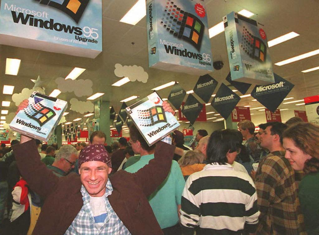 Mikol Furneaux (L) waves two packages of Windows 95 software in the first store in Australia to sell the product at midnight Aug. 24, 1995. (Torsten Blackwood/AFP via Getty Images)