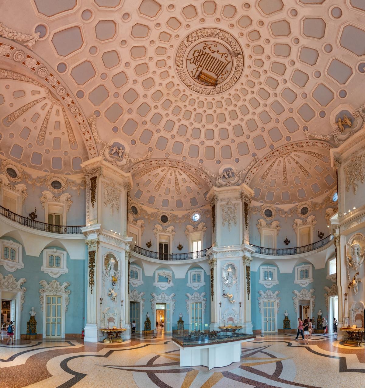 The Salone Nuovo (New Hall) is Palazzo Borromeo’s most spacious room. Used at one time as a ballroom and general space for entertaining, it has a domed, caisson-laden (sunken panels) ceiling supported by enormous two-story columns and balconied half-dome alcoves. White trimmed doors and windows accentuate the room’s blue walls, and the inlaid floor features a large star design—a stark contrast to the florid decorative moldings, including cherubs and medallions. (trabantos/Shutterstock)