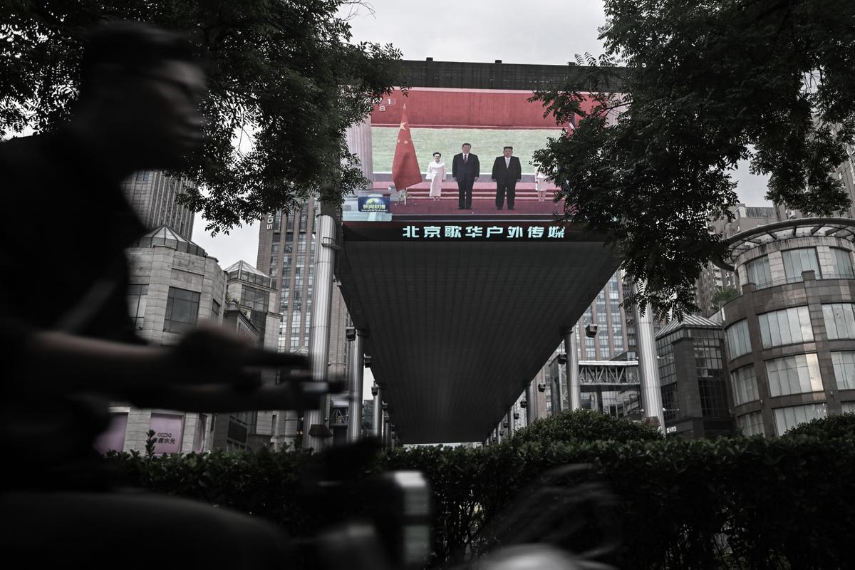 A man rides past a giant screen displayed outside a shopping mall in Beijing on June 8, 2026, showing a news program about the meeting between China's President Xi Jinping and North Korean leader Kim Jong Un held in North Korea. (Pedro Pardo/AFP via Getty Images)