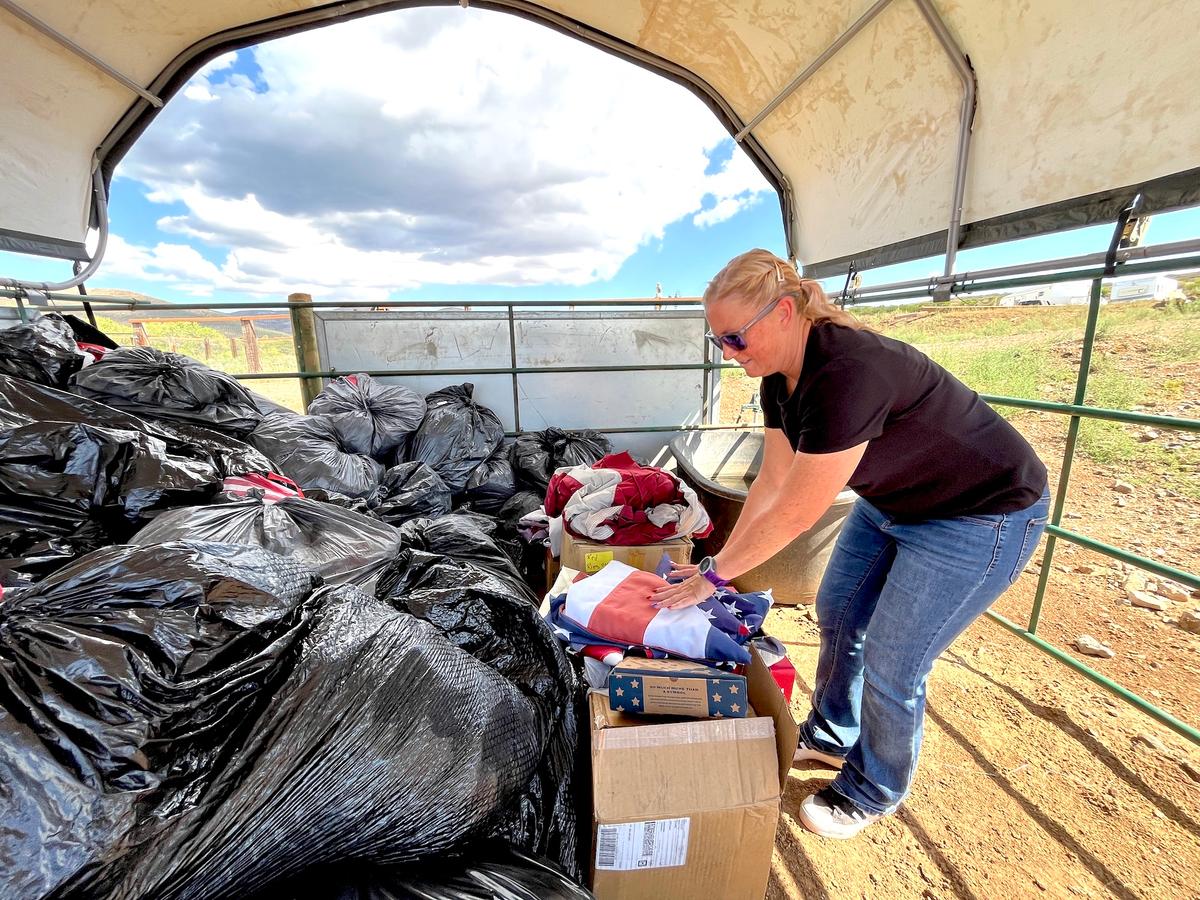 Volunteer Angela Mandich sorts through bags filled with old and worn American flags during a flag retirement ceremony in Mayer, Ariz., on Flag Day, June 14, 2026. (Allan Stein/The Epoch Times)