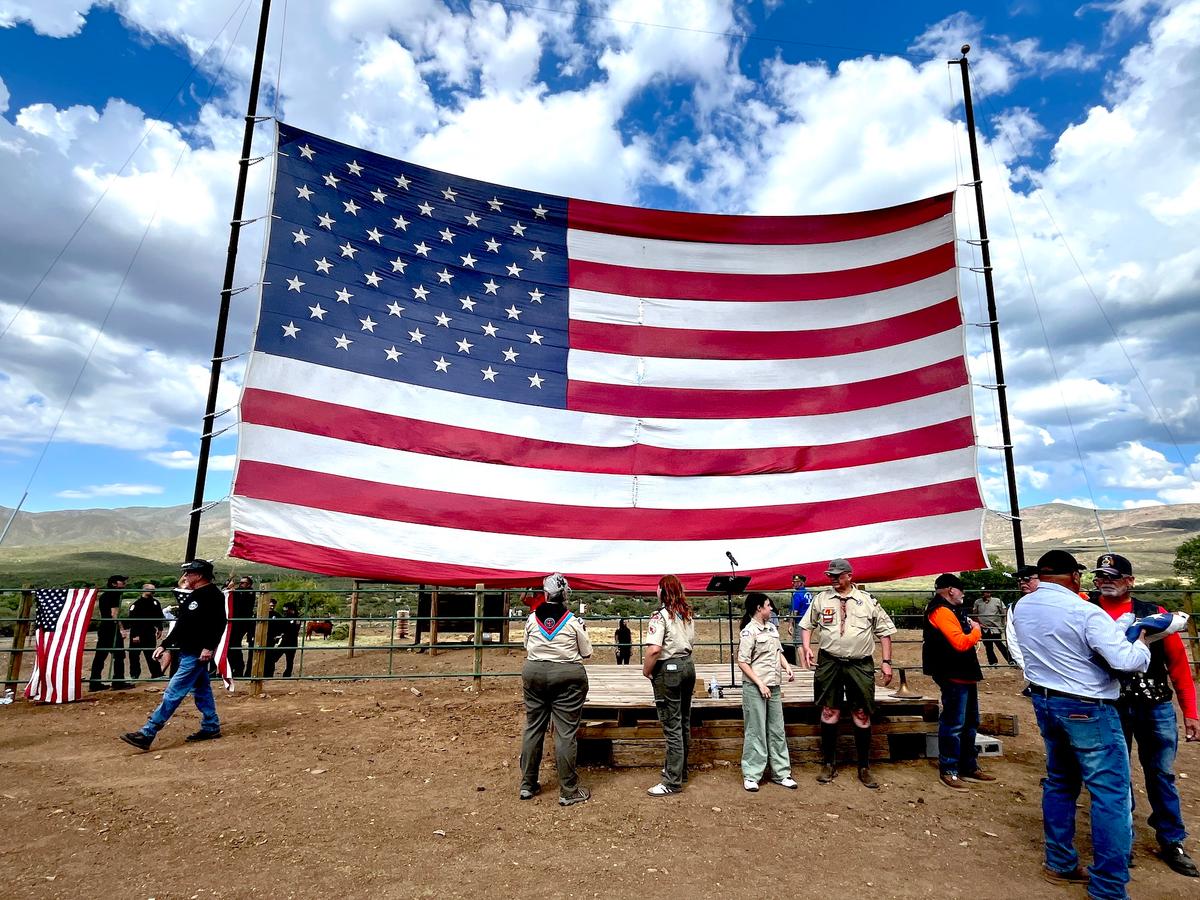 A 30-by-60-foot flag serves as the backdrop for a Flag Day ceremony in Mayer, Ariz., on June 14, 2026. (Allan Stein/The Epoch Times)