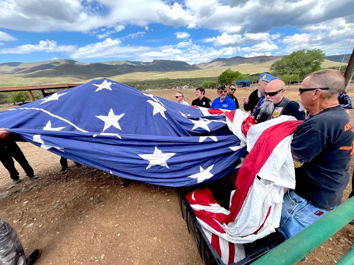 Volunteers carry a 30-by-60-foot American flag to its twin flagpoles during a Flag Day ceremony in Mayer, Ariz., on June 14, 2026. (Allan Stein/The Epoch Times)