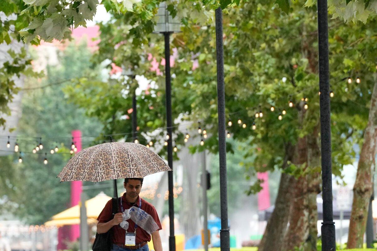 A convention attendee walks in the rain outside the George R. Brown Convention Center on June 17, 2026, in Houston, Texas. (Kevin M. Cox/AP Photo)