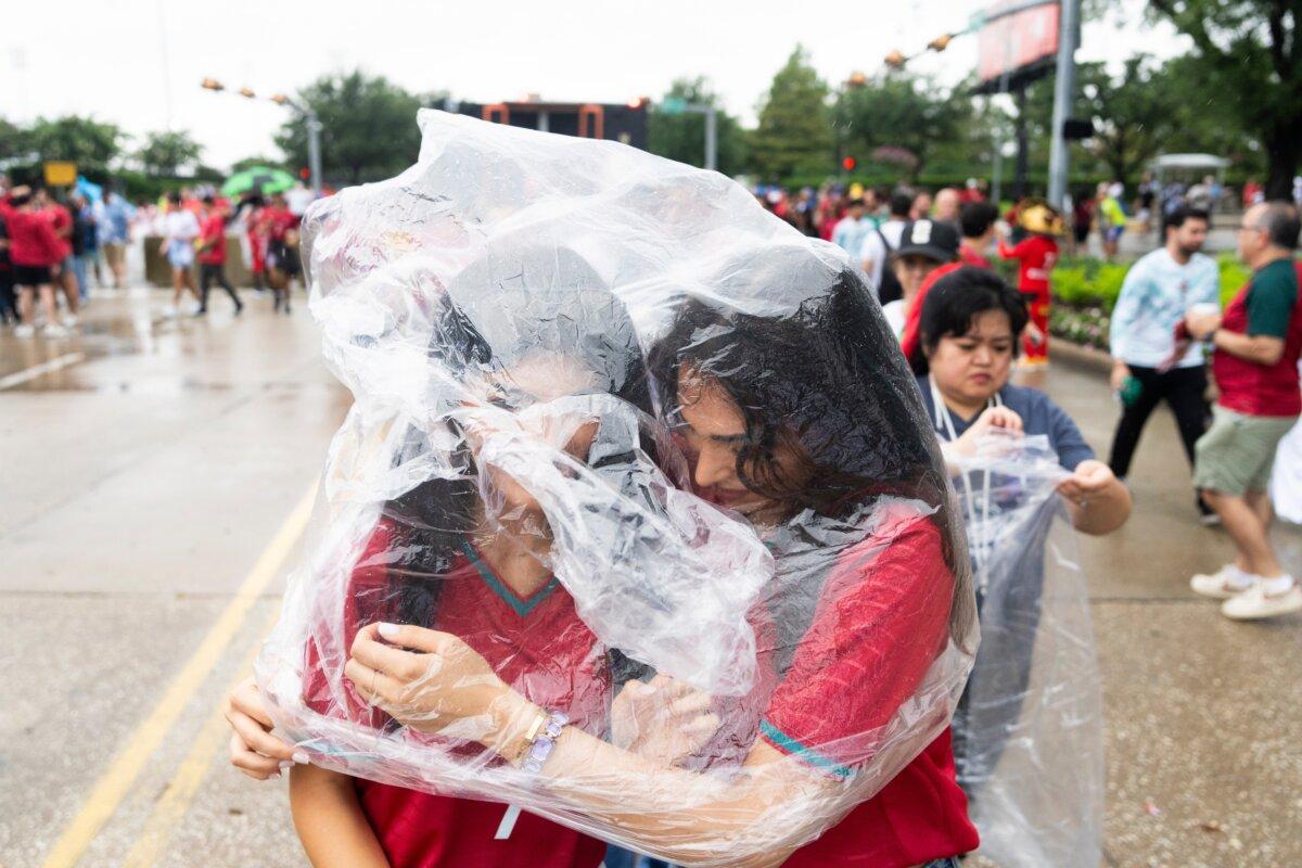 Portugal fans share a poncho to protect themselves from the rain as they wait to enter Houston Stadium before a FIFA World Cup match between Portugal and Congo in Houston, Texas, on June 17, 2026. (Jason Fochtman/Houston Chronicle via AP)